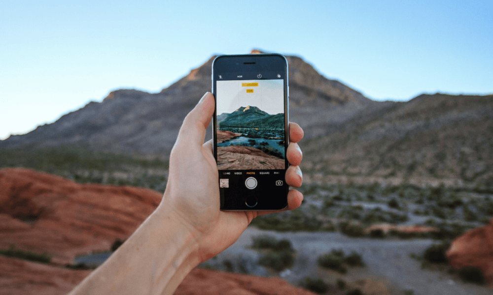 Una persona con un smartphone haciendo una foto a unas montañas